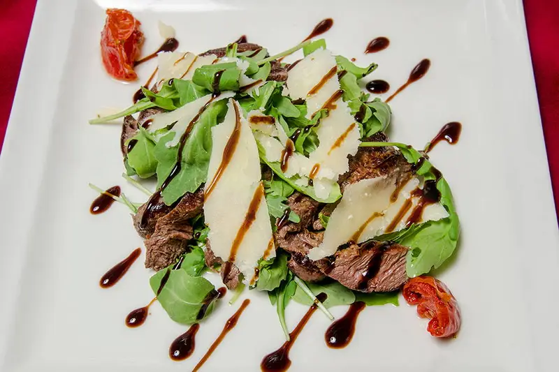 La tagliata de boeuf à la florentine : Lamelles de boeuf saignantes, poêlées avec du vinaigre balsamique, servies sur un lit de roquette et copeaux de parmesan.