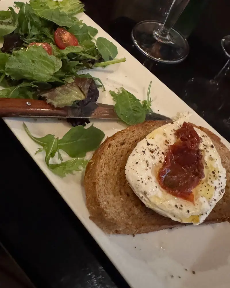Burrata des Pouilles : La burrata est une boule de fromage au coeur crémeux, d’une grande finesse. Elle est servie sur une tranche de pain grillée, arrosée d’un filet d’huile d’olive, avec des tomates confites et un nid de salade.