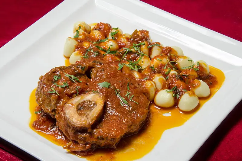 L’osso buco de veau : Un tendre morceau de jarret de veau mijoté dans une sauce tomate aux herbes de Provence ; accompagné de gnocchi maison.